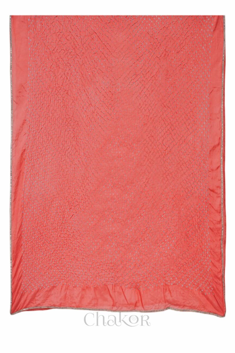 Close up of peach Bandhani mulberry silk dupatta with tie-dye dot pattern & detailed with golden lace.