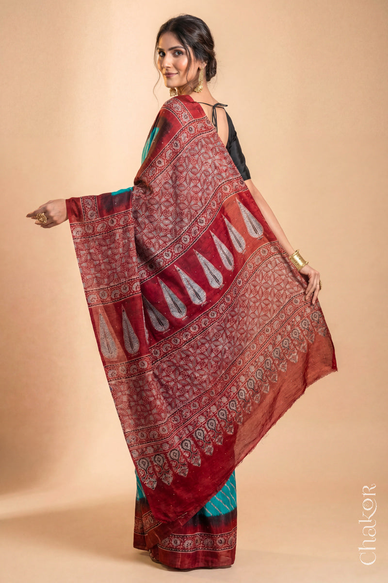 Woman wearing Peacock Blue Bandhani Saree with Natural Red Ajrakh printed border and pallu in pure gaji silk with traditional bandhej tie-dye & mukaish embroidery, handcrafted in Kutch.
