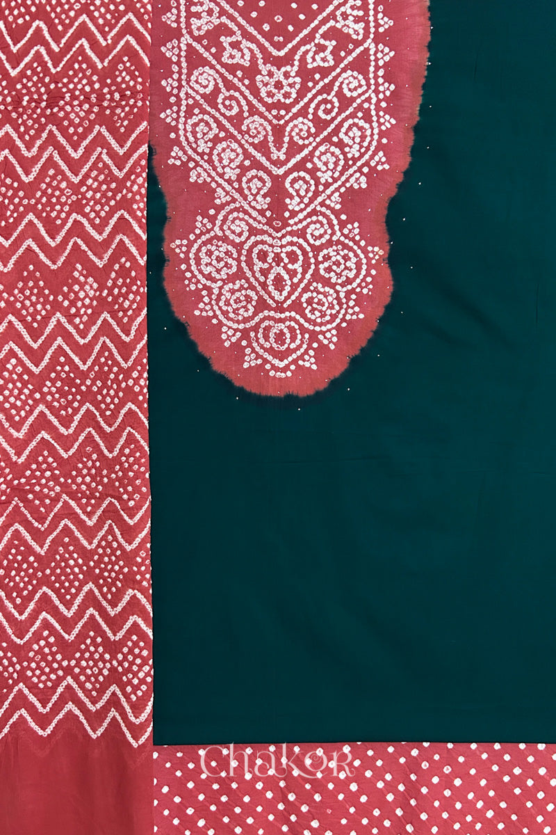 A dark green kurta set fabric with intricate bandhani & dusty red yoke with sparkly mukaish embroidery, paired with a bottom & odhani placed on the left side featuring a zigzag design.