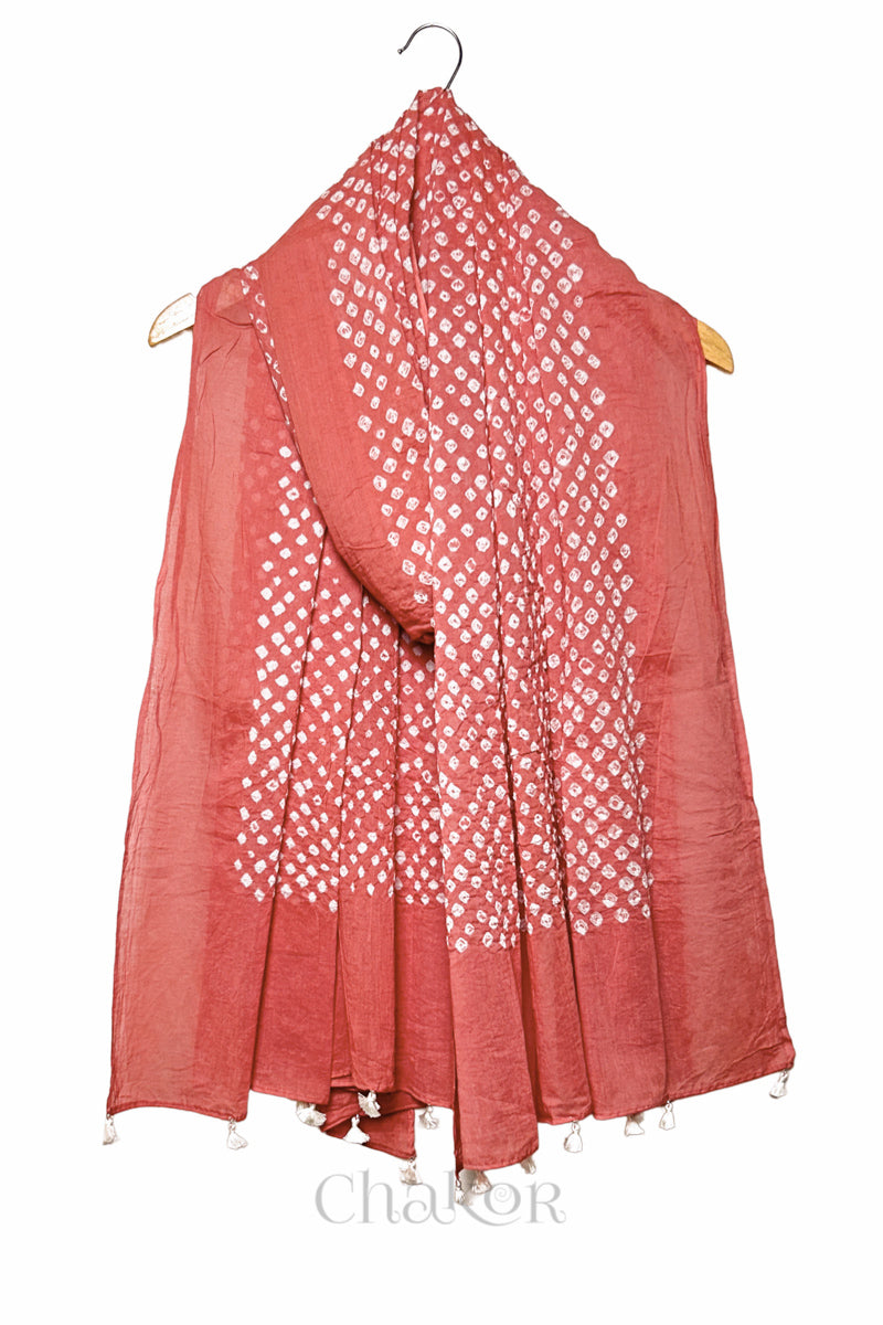 Dark Peach Bandhani mul cotton dupatta draped on hanger showing tie-dye dot pattern and tasselled edge.