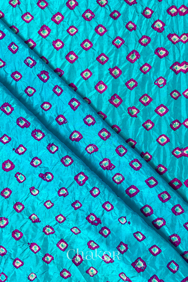 Turquoise Blue Mulberry silk fabric showcasing dual colouPink bandhani patterns with folds and Chakor brand watermark.