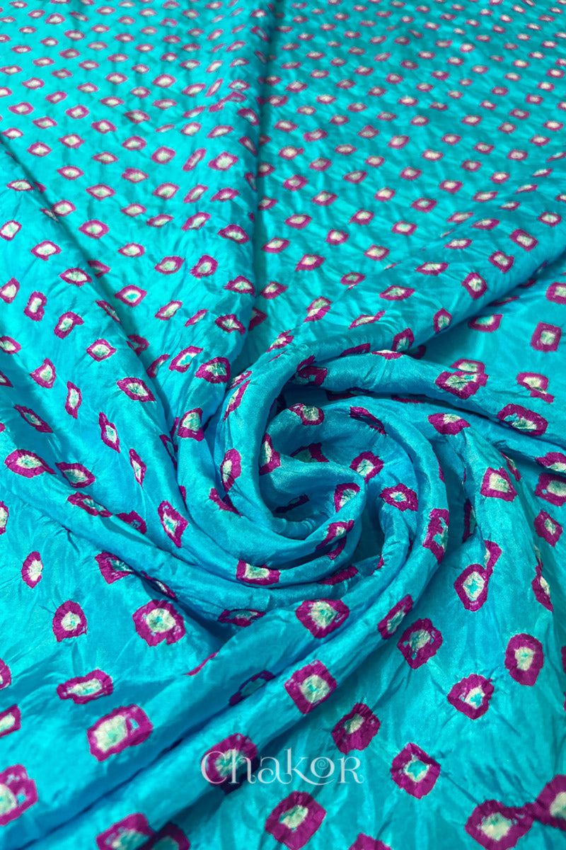 Turquoise Blue Mulberry silk fabric with dual colour Pink bandhani dots, arranged in a swirling design & Chakor brand watermark.