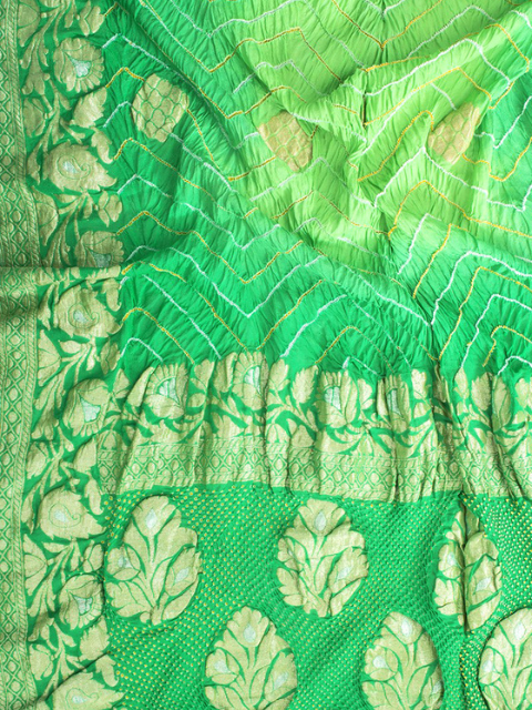 Close-up of a green bandhani saree  & leaf patterns in zari weaving.