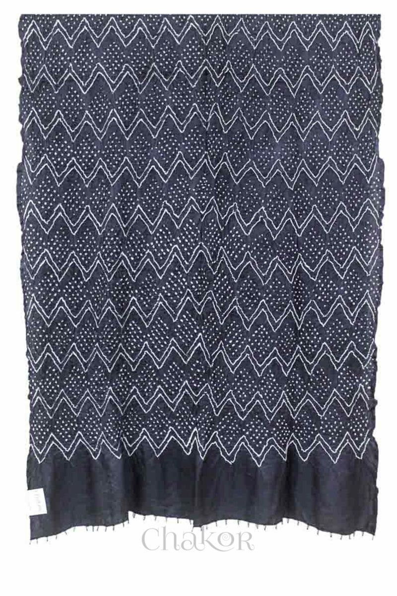 Full view of a charcoal grey rai bandhej dupatta in gaji silk, pallu edge detailed with beads.Text reads Chakor brand watermark.