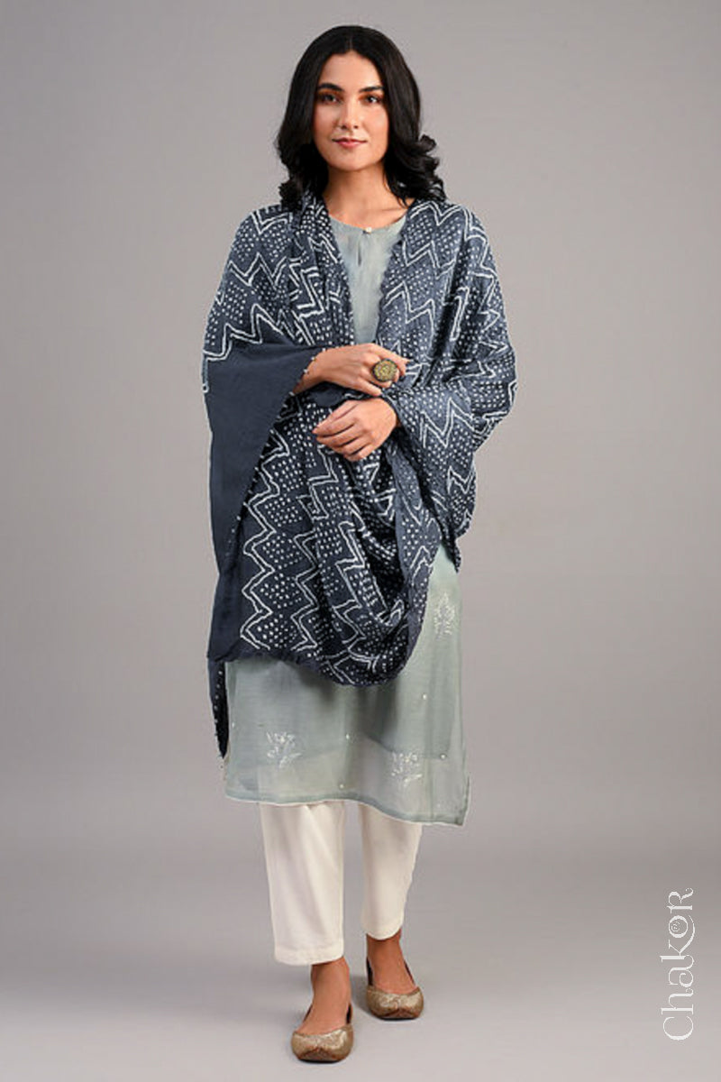 Women wearing  a charcoal grey rai bandhej dupatta in gaji silk, pallu edge detailed with beads.Text reads Chakor brand watermark.