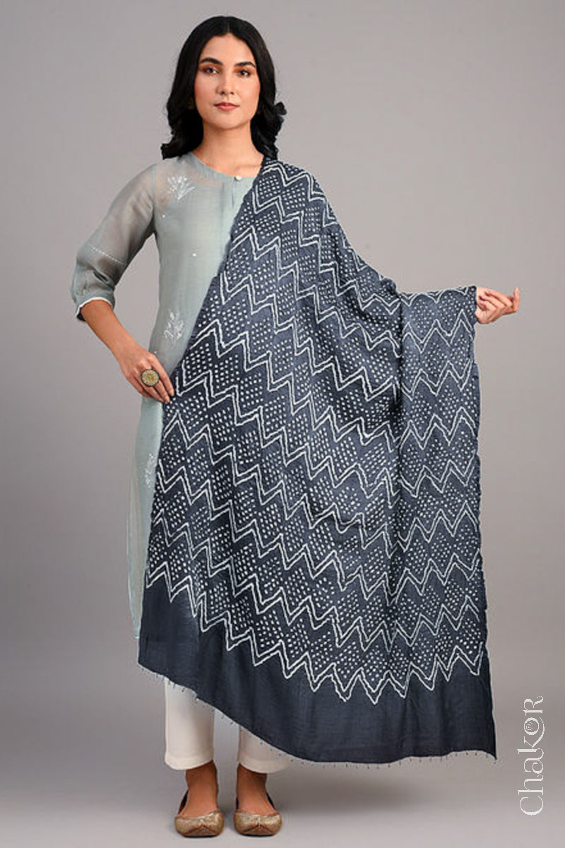 Women wearing  a charcoal grey rai bandhej dupatta in gaji silk, pallu edge detailed with beads.Text reads Chakor brand watermark.