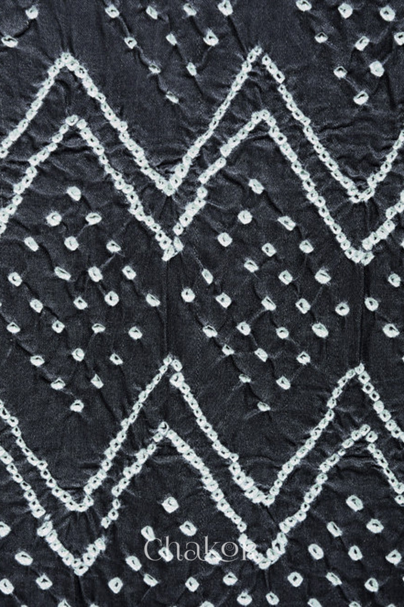 close-up of a charcoal grey rai bandhej dupatta in gaji silk,pallu edge detailed with beads.Text reads Chakor brand watermark.
