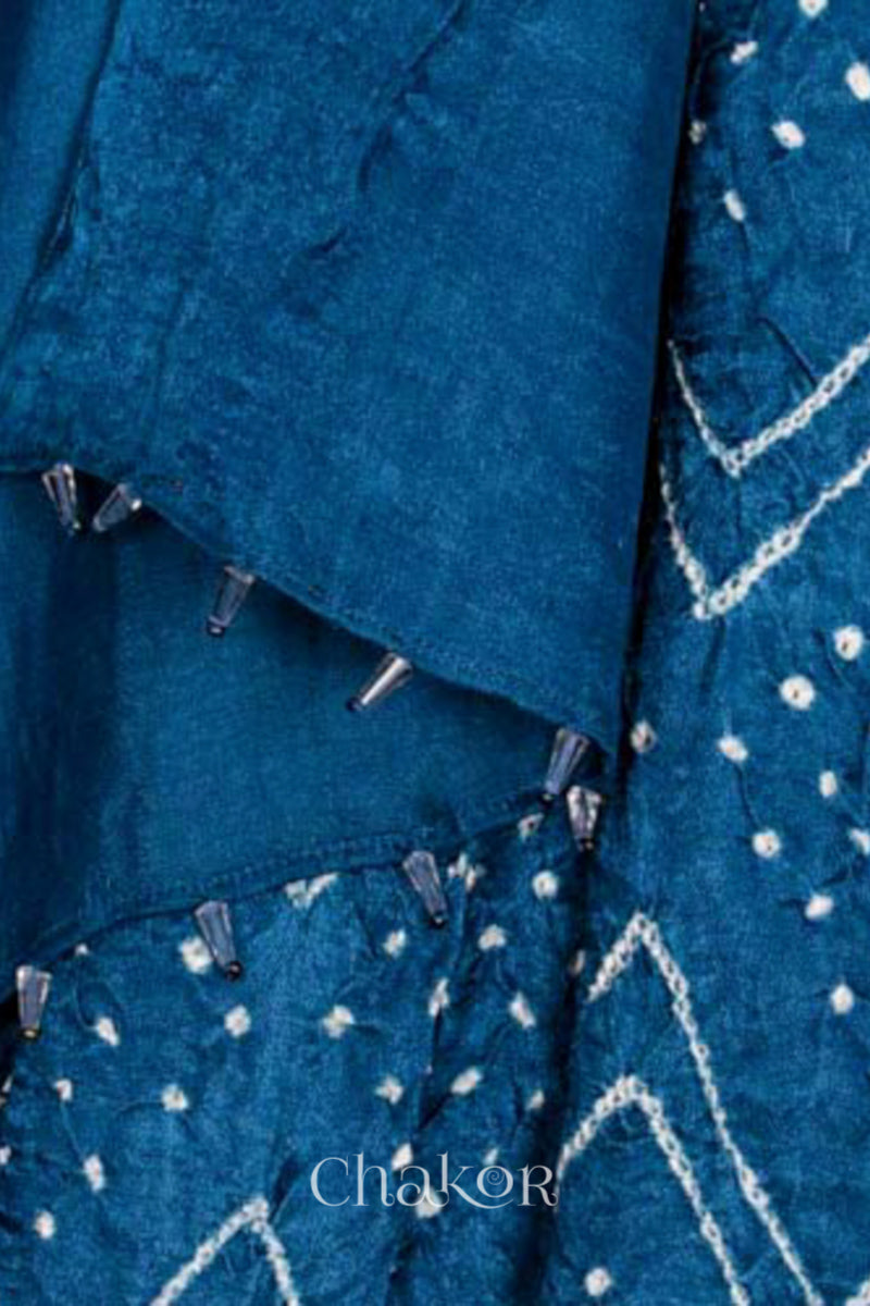 close-up of blue rai bandhej dupatta in gaji silk ,pallu edge detailed with beads.Text reads Chakor brand watermark.

