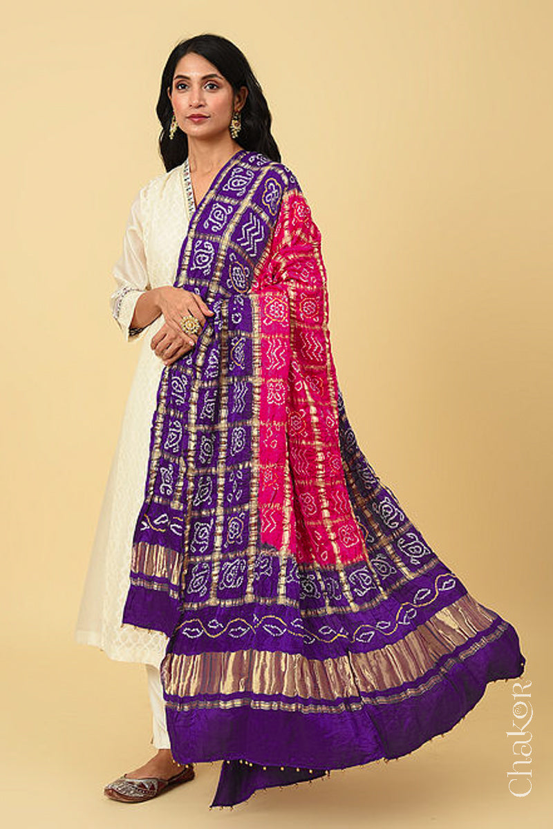 Woman wearing Pink Purple Bandhani Gharchola Gaji Silk Dupatta on beige kurta set.
