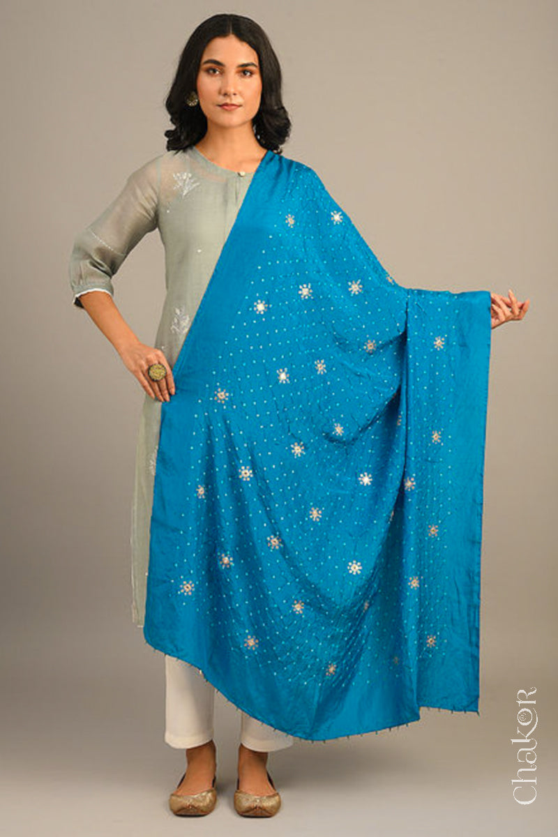 Women wearing peacock blue Bandhani mulberry silk dupatta with tie-dye dot pattern & detailed with Mirror work, Sequin work, Zari work, Bead edging draped over a grey kurta.