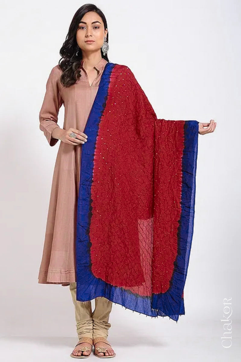 Woman wearing red & navy border Bandhani mulberry silk dupatta with tie-dye dot pattern & detailed with Bead edging.
