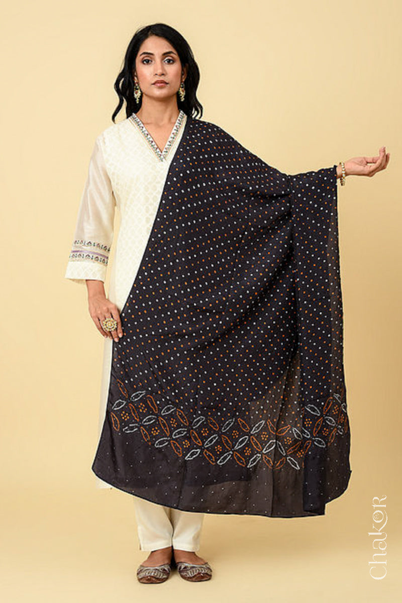 Woman wearing black Bandhani mulberry silk dupatta with multi colour tie-dye dot pattern & detailed with mukaish work &  Bead edging.