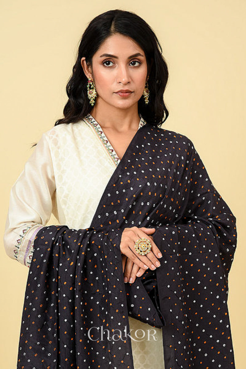 Woman wearing black Bandhani mulberry silk dupatta with multi colour tie-dye dot pattern & detailed with mukaish work &  Bead edging.