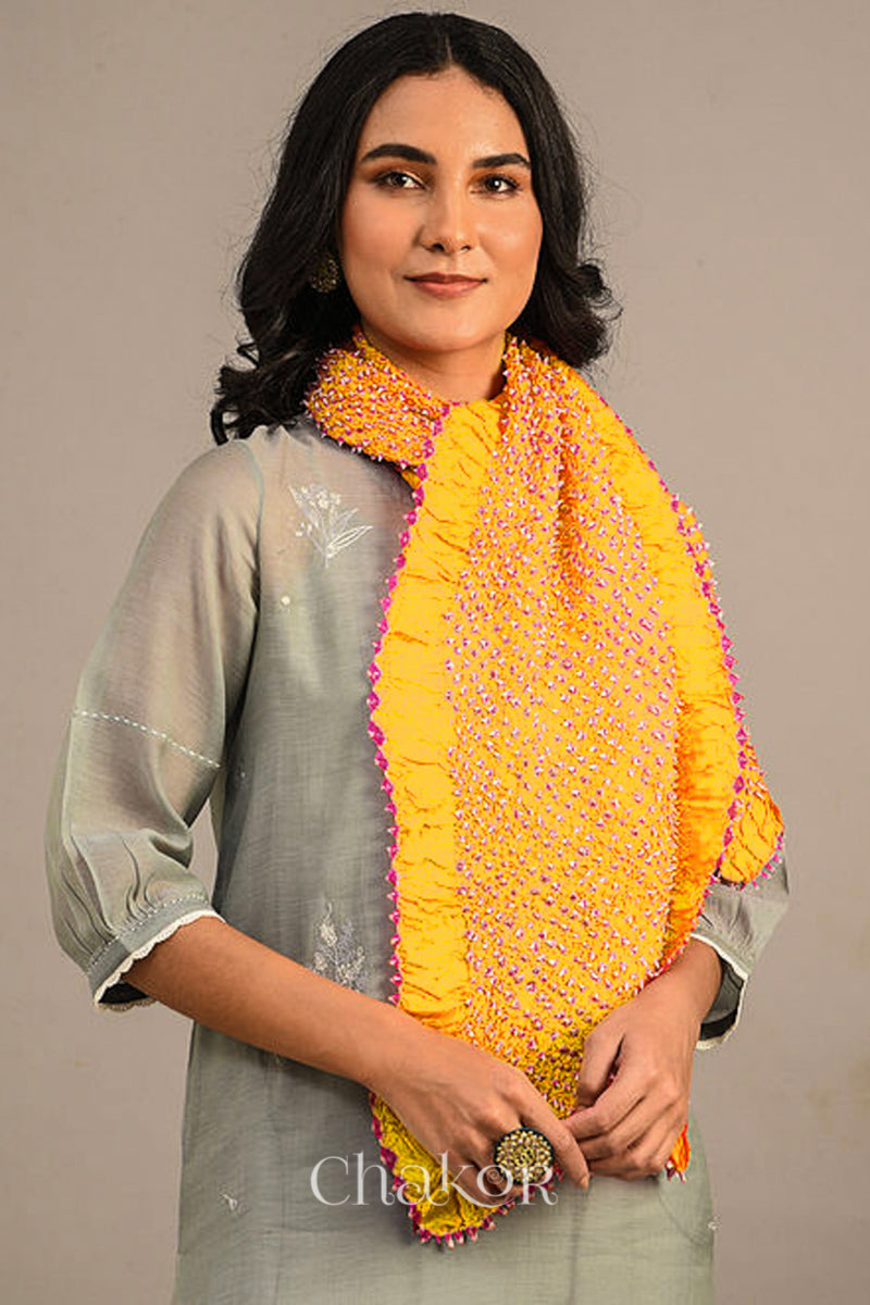 Woman wearing yellow Bandhani mulberry silk stole with pink tie-dye dot pattern.