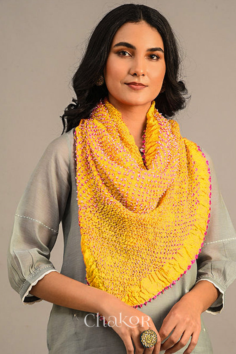Woman wearing yellow Bandhani mulberry silk stole with pink tie-dye dot pattern.