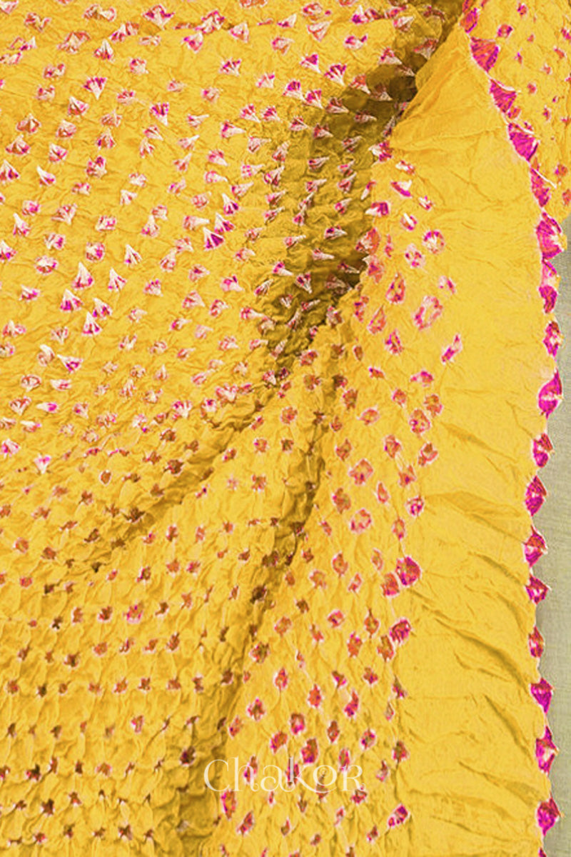 Close up of yellow Bandhani mulberry silk stole with pink tie-dye dot pattern.
