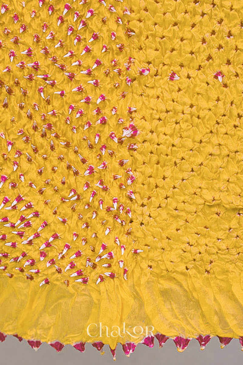 Close up of yellow Bandhani mulberry silk stole with pink tie-dye dot pattern.