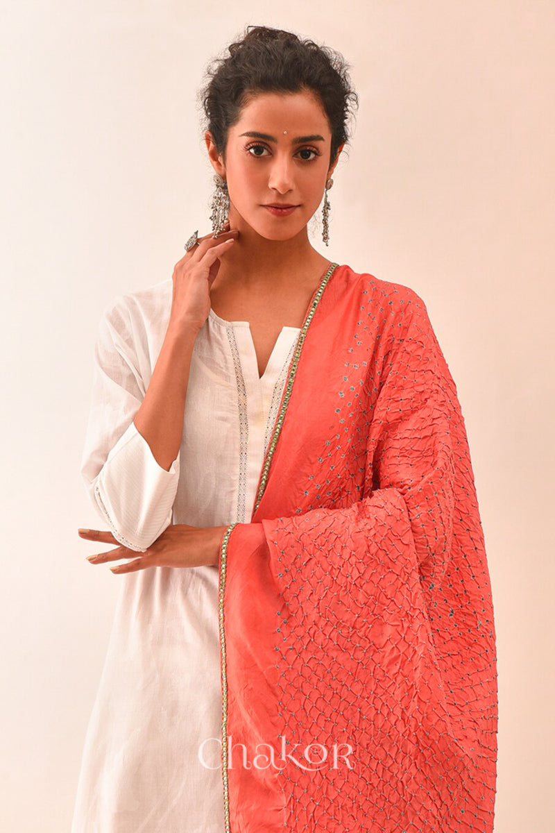 Woman wearing peach Bandhani mulberry silk dupatta with tie-dye dot pattern & detailed with golden lace.