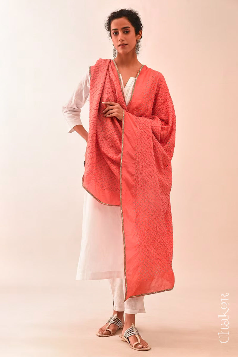 Woman wearing peach Bandhani mulberry silk dupatta with tie-dye dot pattern & detailed with golden lace.