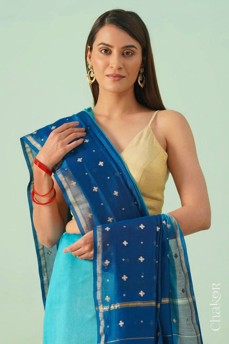 Front close view of turquoise navy shaded Chanderi silk cotton saree showing woven body and embroidered details.
