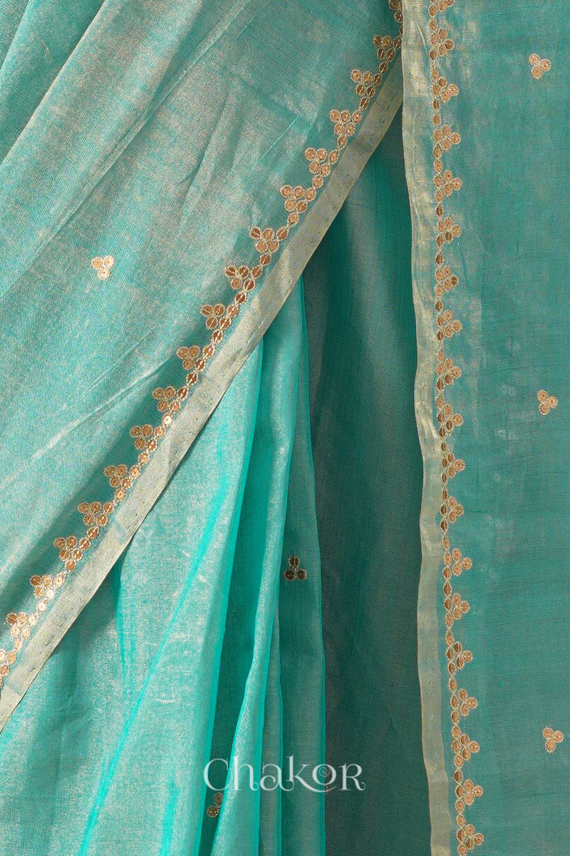 Close-up of embroidered sequin tikki border and zari details on peacock blue Chanderi tissue silk cotton saree.

