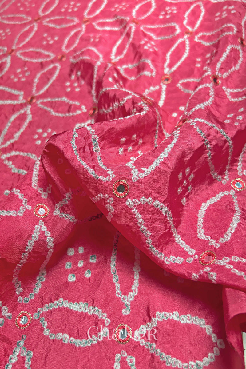 Close-up of a pink saree in silk fabric with intricate white bandhani patterns that are mirror embroidered and 'Chakor' branding.
