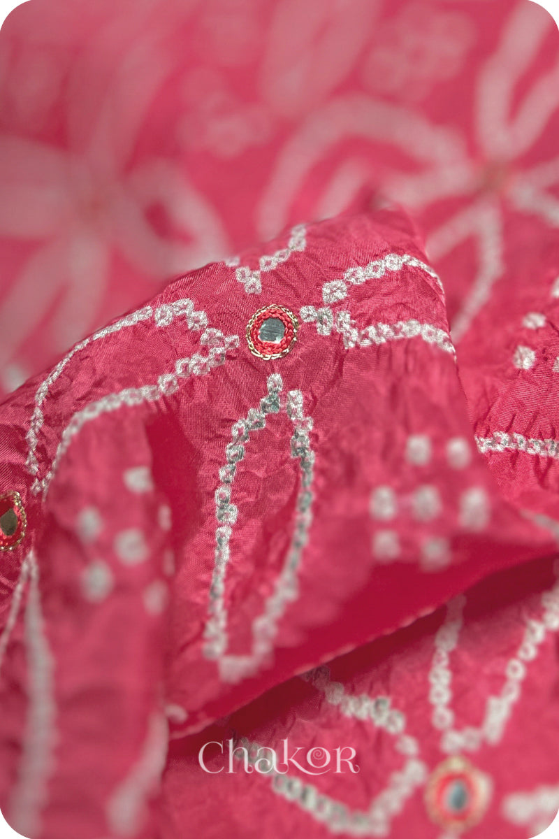 Close-up of a pink saree in silk fabric with intricate white bandhani patterns that are mirror embroidered and 'Chakor' branding.
