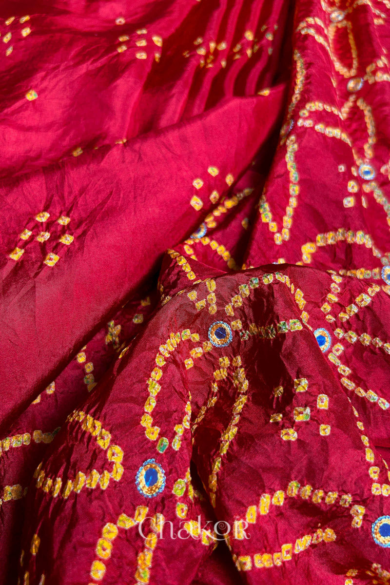 Pleated view of Red Bandhani Mulberry Silk Saree handcrafted with yellow bandhej dots and mirror embroidery.