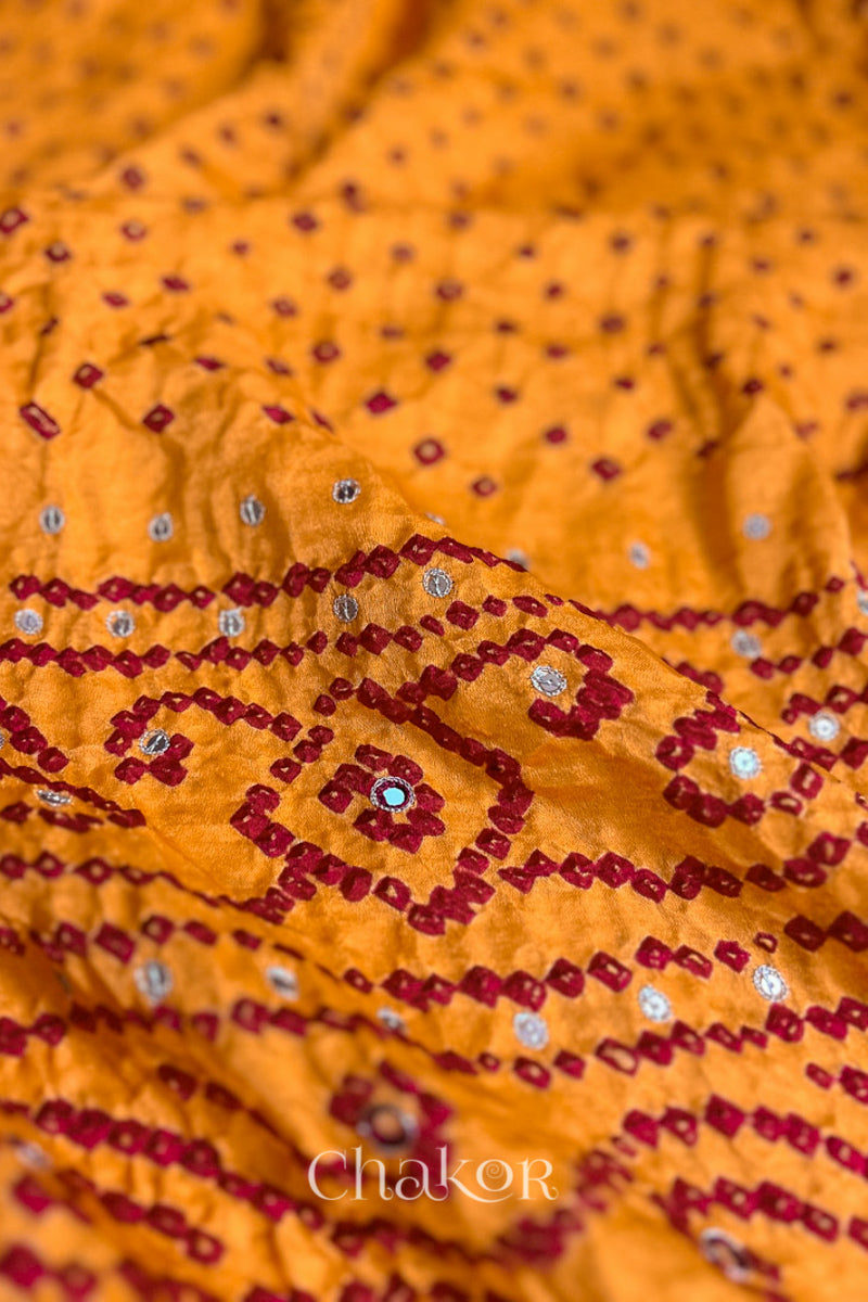 Close up of traditional Yellow Bandhani Gaji Silk Handcrafted Saree, with rai bandhej patterns in red dots and mirror and sequins embroidery.