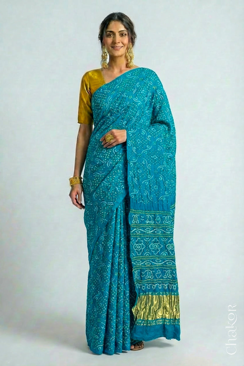 Woman wearing Hancrafted Peacock Blue Bandhani Gaji Silk Saree, with traditional rai bandhej patterns and mukaish embroidery.