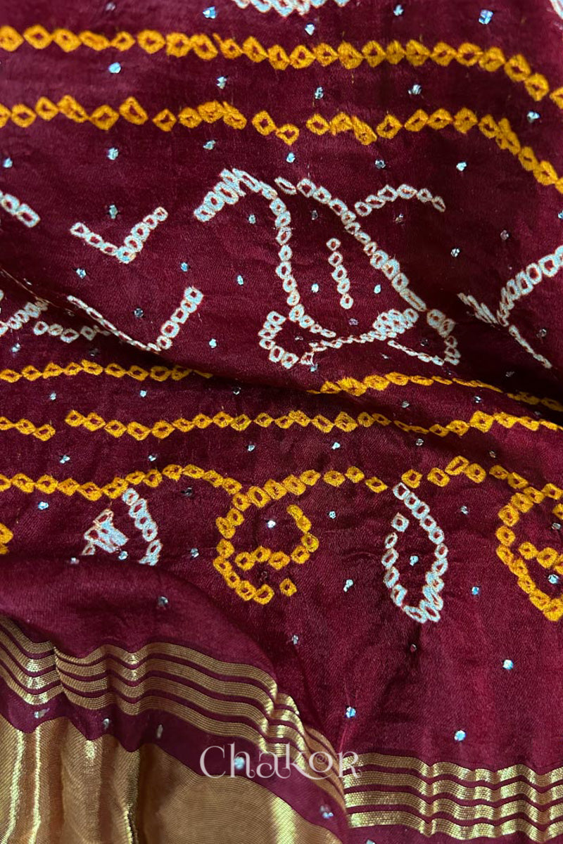 Close up of Handcrafted Maroon Bandhani Gaji Silk Saree with traditional rai bandhej patterns and mukaish embroidery.