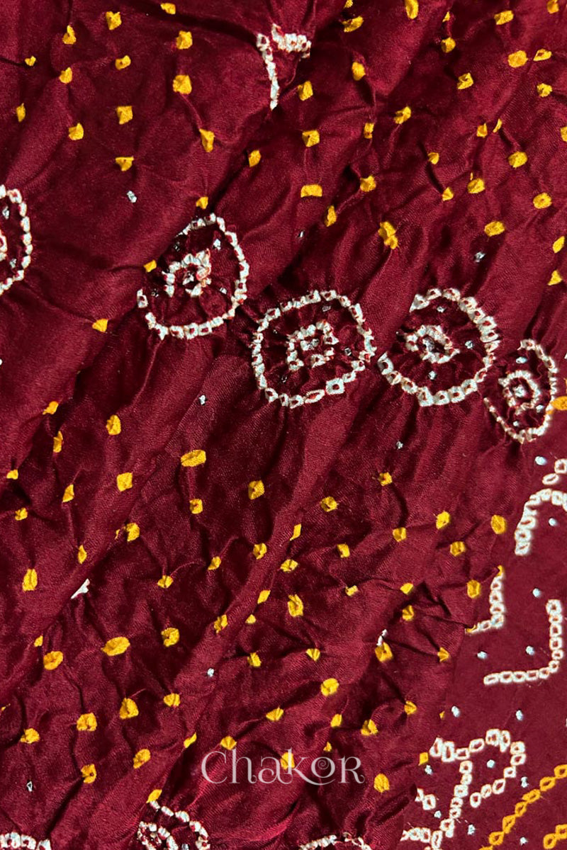 Close up of pleated body of Handcrafted Maroon Bandhani Gaji Silk Saree with traditional rai bandhej patterns and mukaish embroidery.