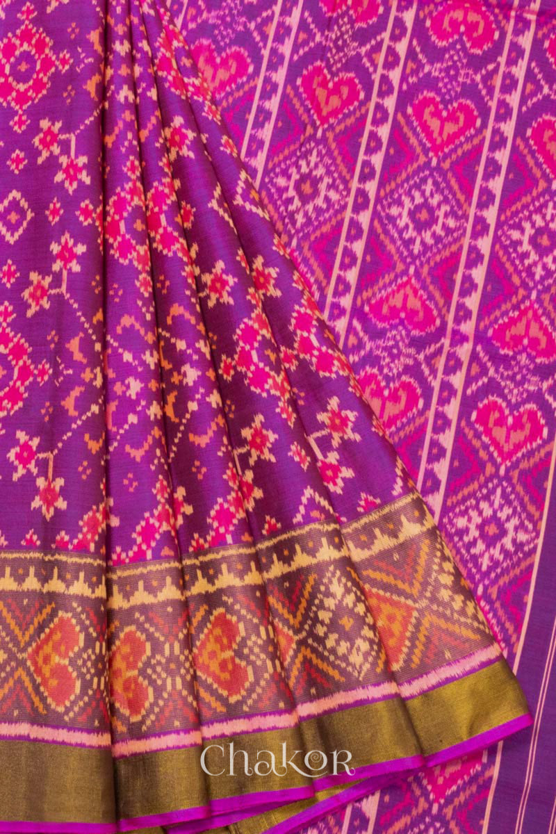 Close up of Handloom Magenta Pink Rajkoti Patola Ikat Mulberry Silk Saree with tissue borders, woven using traditional designs in Gujarat.