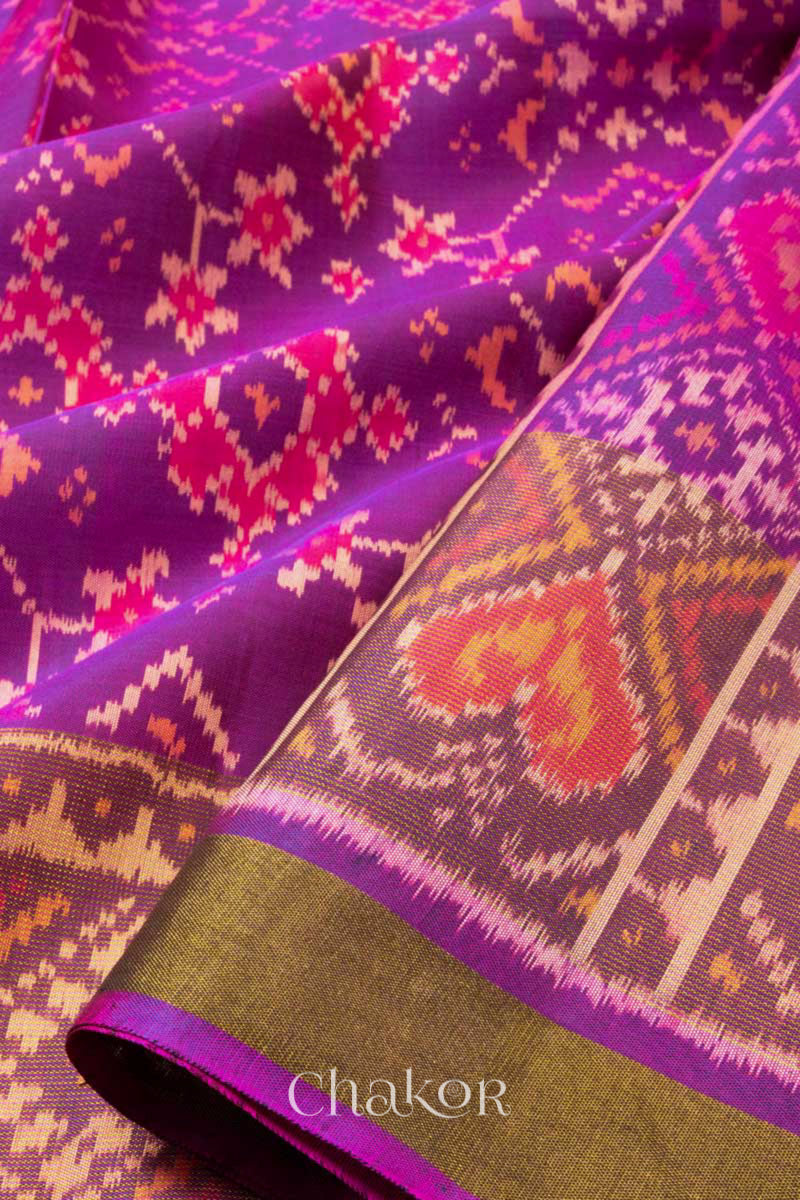 Close up of Handloom Magenta Pink Rajkoti Patola Ikat Mulberry Silk Saree with tissue borders, woven using traditional designs in Gujarat.
