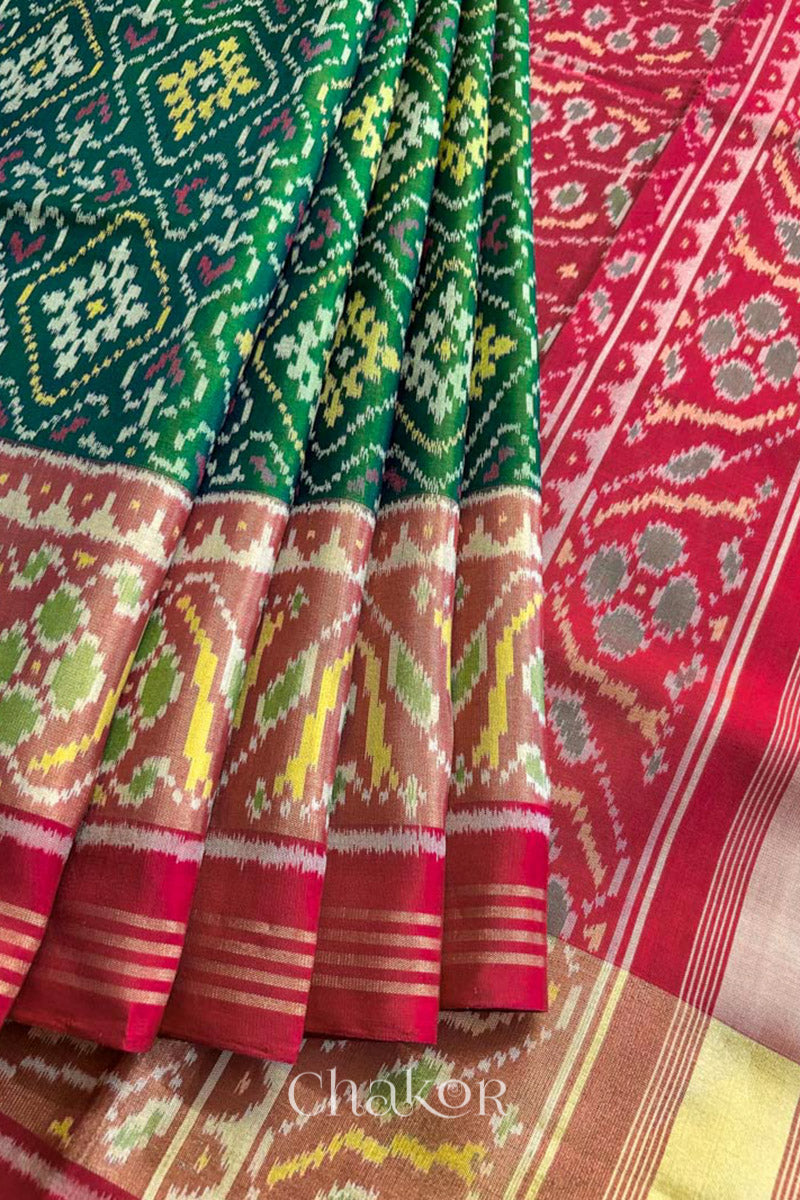 Close up of Handloom Green Rajkoti Patola Ikat Mulberry Silk Saree with red border pallu, woven using traditional designs in Gujarat.