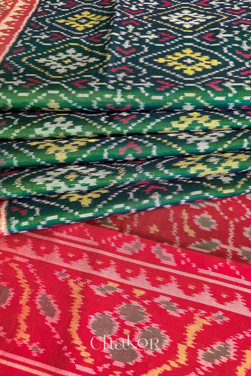 Close up of Handloom Green Rajkoti Patola Ikat Mulberry Silk Saree with red border pallu, woven using traditional designs in Gujarat.