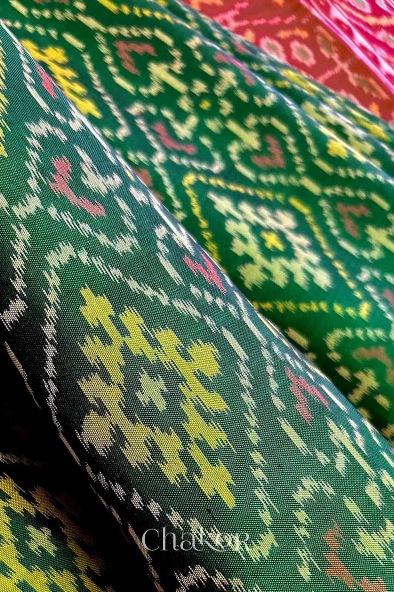 Close up of Handloom Green Rajkoti Patola Ikat Mulberry Silk Saree with red border pallu, woven using traditional designs in Gujarat.