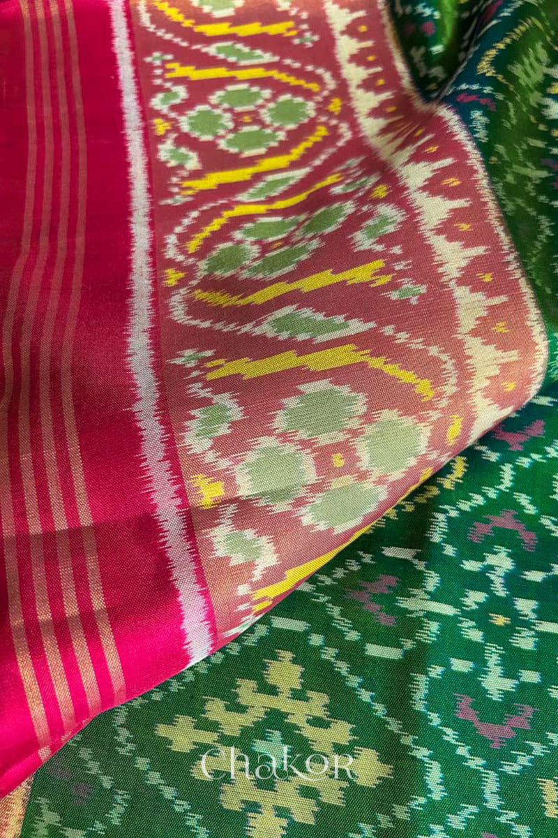 Close up of Handloom Green Rajkoti Patola Ikat Mulberry Silk Saree with red border pallu, woven using traditional designs in Gujarat.