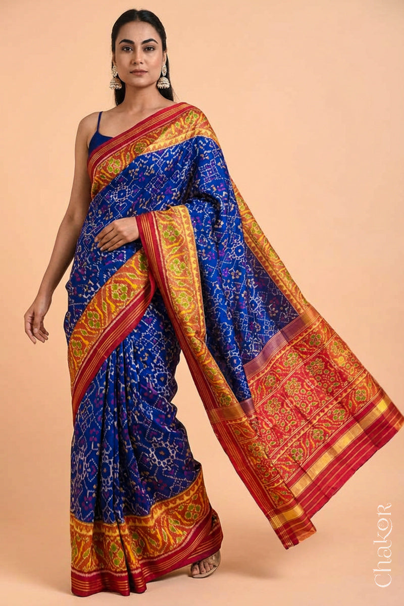Woman wearing Handloom Blue and Red Ikat Patola Mulberry Pure Silk Saree, with traditional design handcradted in Rajkot.