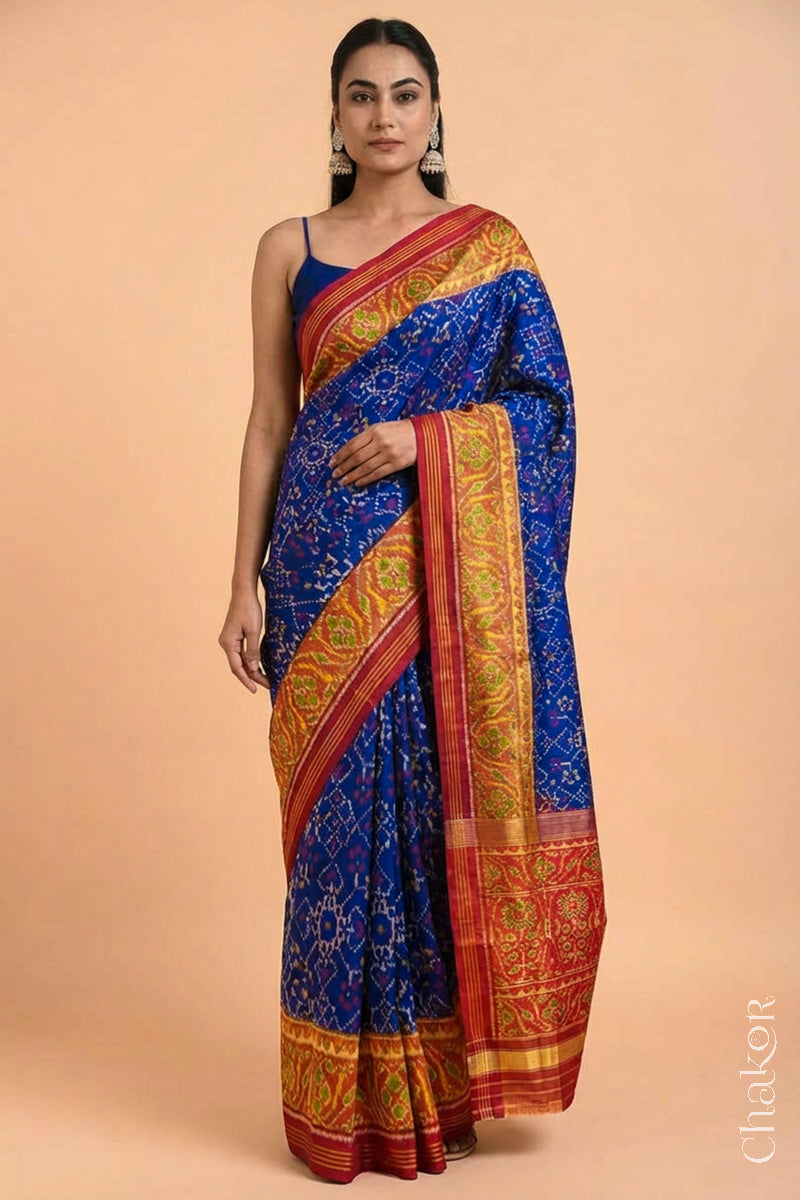Woman wearing Handloom Blue and Red Ikat Patola Mulberry Pure Silk Saree, with traditional design handcradted in Rajkot.