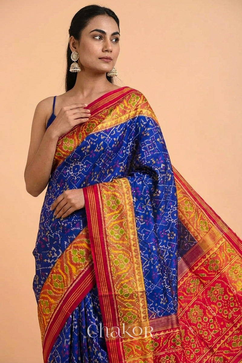 Woman wearing Handloom Blue and Red Ikat Patola Mulberry Pure Silk Saree, with traditional design handcradted in Rajkot.