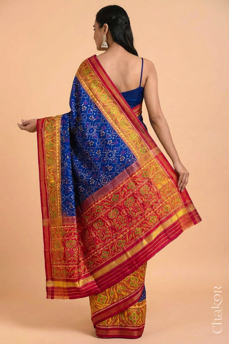 Woman wearing Handloom Blue and Red Ikat Patola Mulberry Pure Silk Saree, with traditional design handcradted in Rajkot.