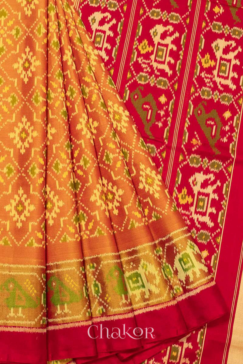 Close up of Handloom Rust Rajkoti Patola Ikat Mulberry Silk Saree with Red borders & pallu, woven using traditional designs in Gujarat.
