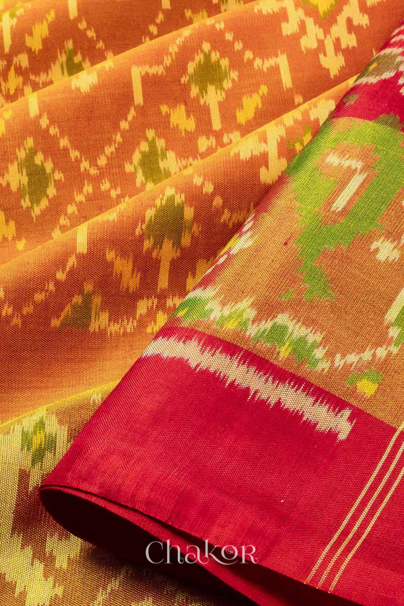 Close up of Handloom Rust Rajkoti Patola Ikat Mulberry Silk Saree with Red borders & pallu, woven using traditional designs in Gujarat.