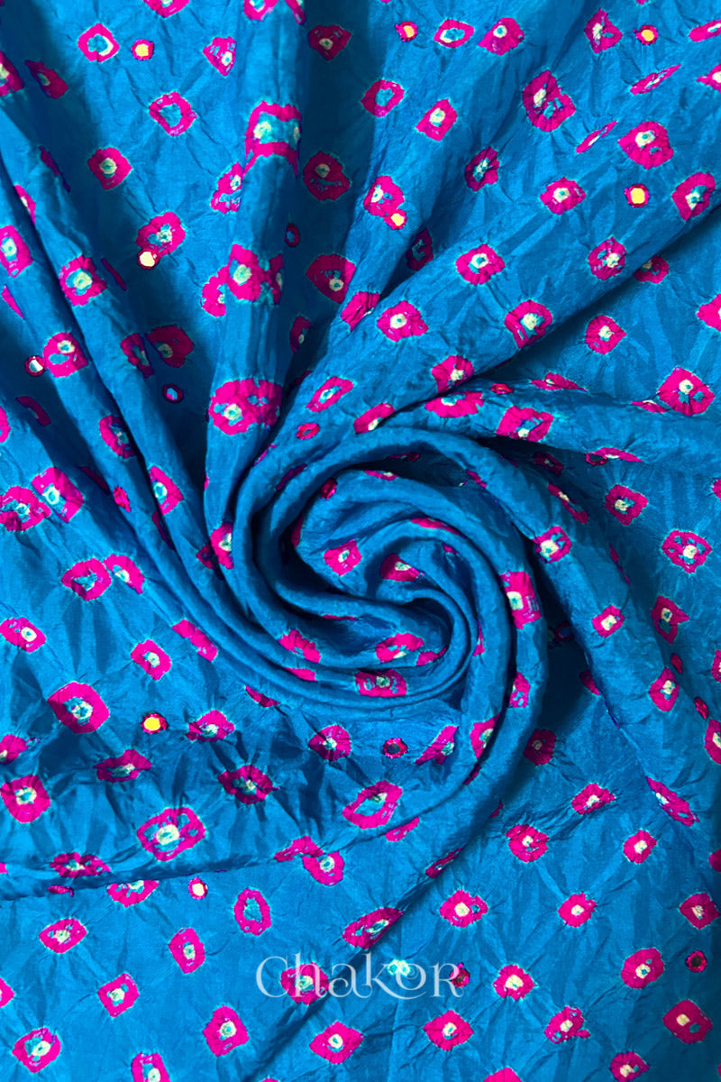 Close up of Peacock Blue Bandhani Mulberry Silk Fabric with pink bandhej dots and mirror embroidery.