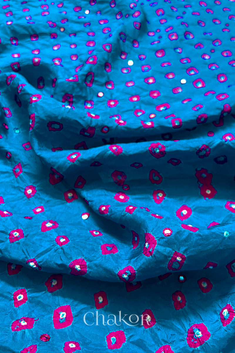 Close up of Peacock Blue Bandhani Mulberry Silk Fabric with pink bandhej dots and mirror embroidery.
