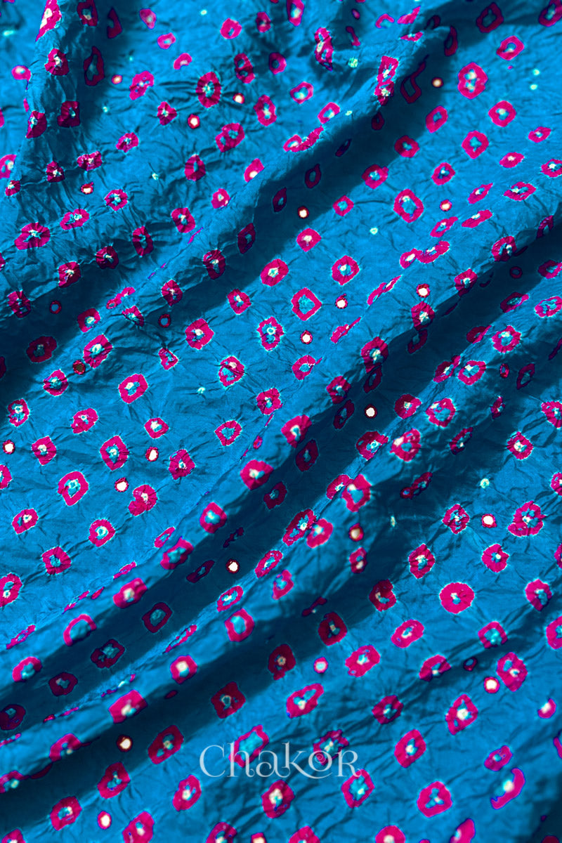 Close up of Peacock Blue Bandhani Mulberry Silk Fabric with pink bandhej dots and mirror embroidery.