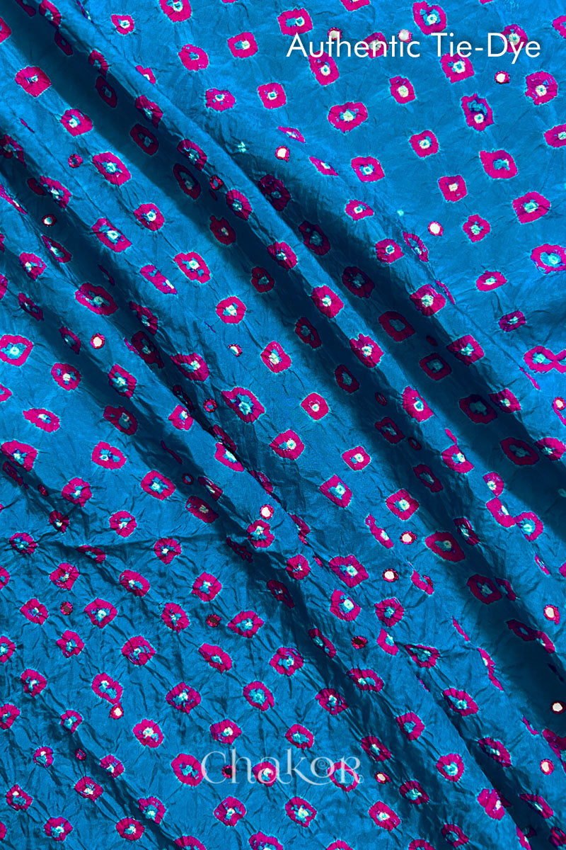 Close up of Peacock Blue Bandhani Mulberry Silk Fabric with pink bandhej dots and mirror embroidery.
