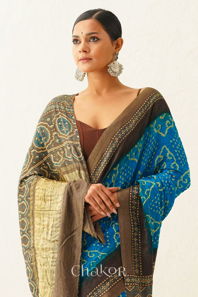 Woman wearing Peacock Blue Bandhani Saree with Brown Ajrakh printed border and pallu in pure gaji silk with traditional bandhej tie-dye, handcrafted in Kutch. 