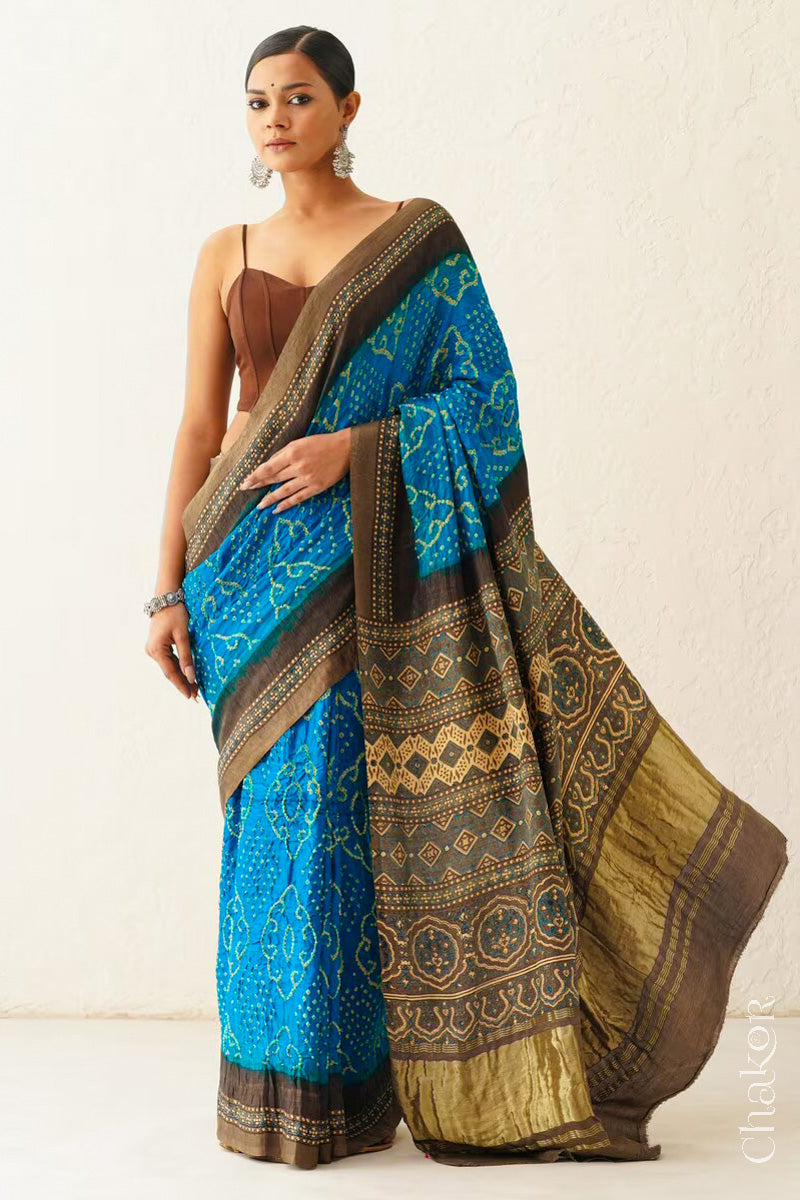 Woman wearing Peacock Blue Bandhani Saree with Brown Ajrakh printed border and pallu in pure gaji silk with traditional bandhej tie-dye, handcrafted in Kutch. 